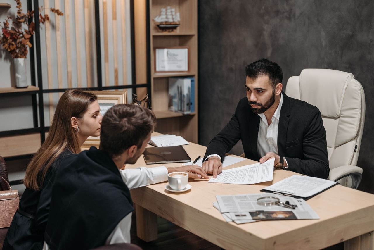 Services Lawyer discussing legal documents with clients at office desk.